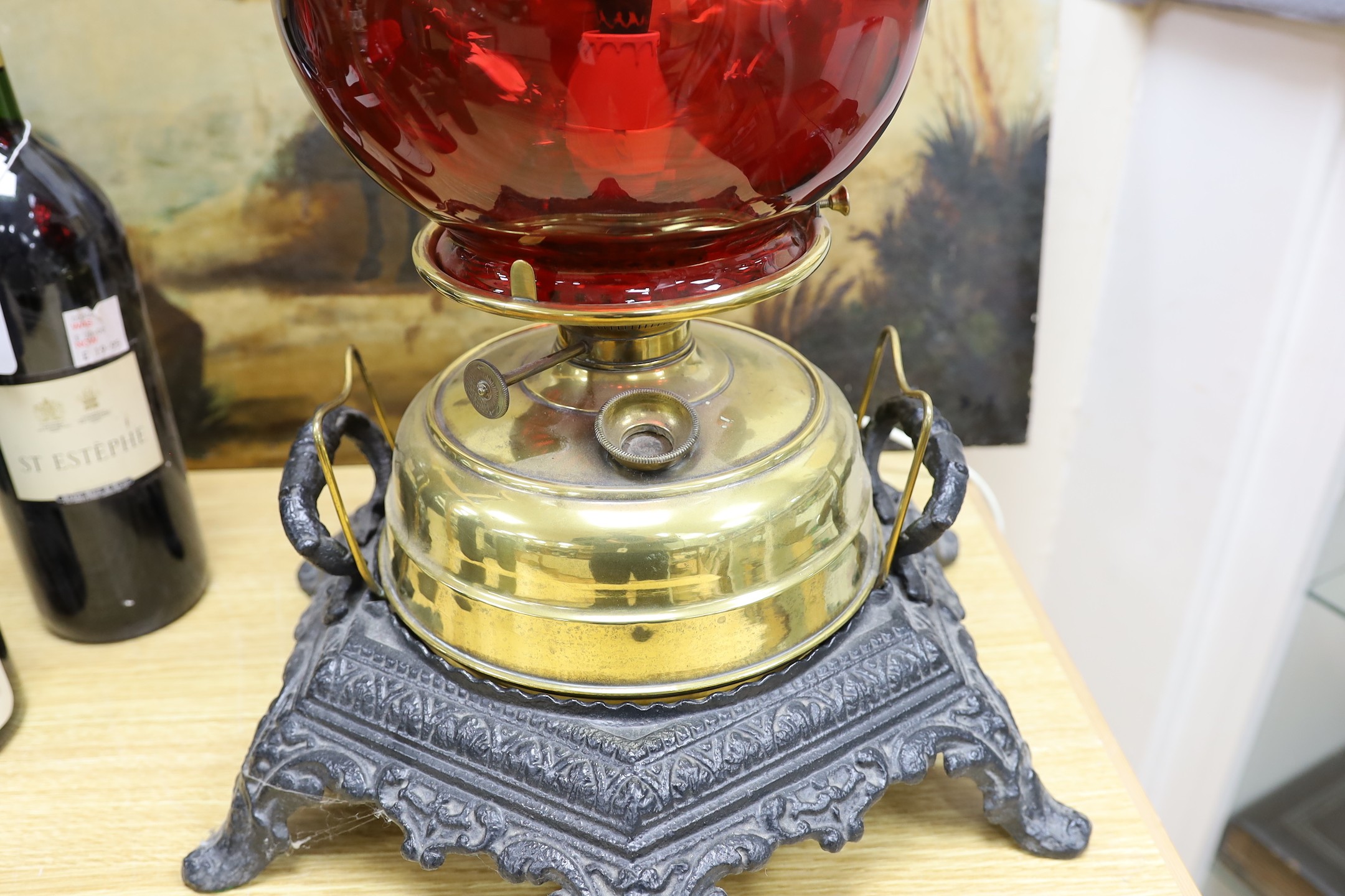 A floor-standing cranberry glass and brass, iron-mounted lamp, converted to a table lamp, 63cms high
